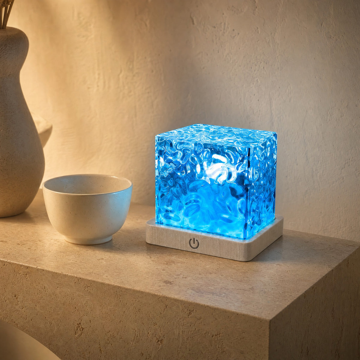 Cube lamp next to a ceramic bowl on a travertine console, showing its compact 11 cm size