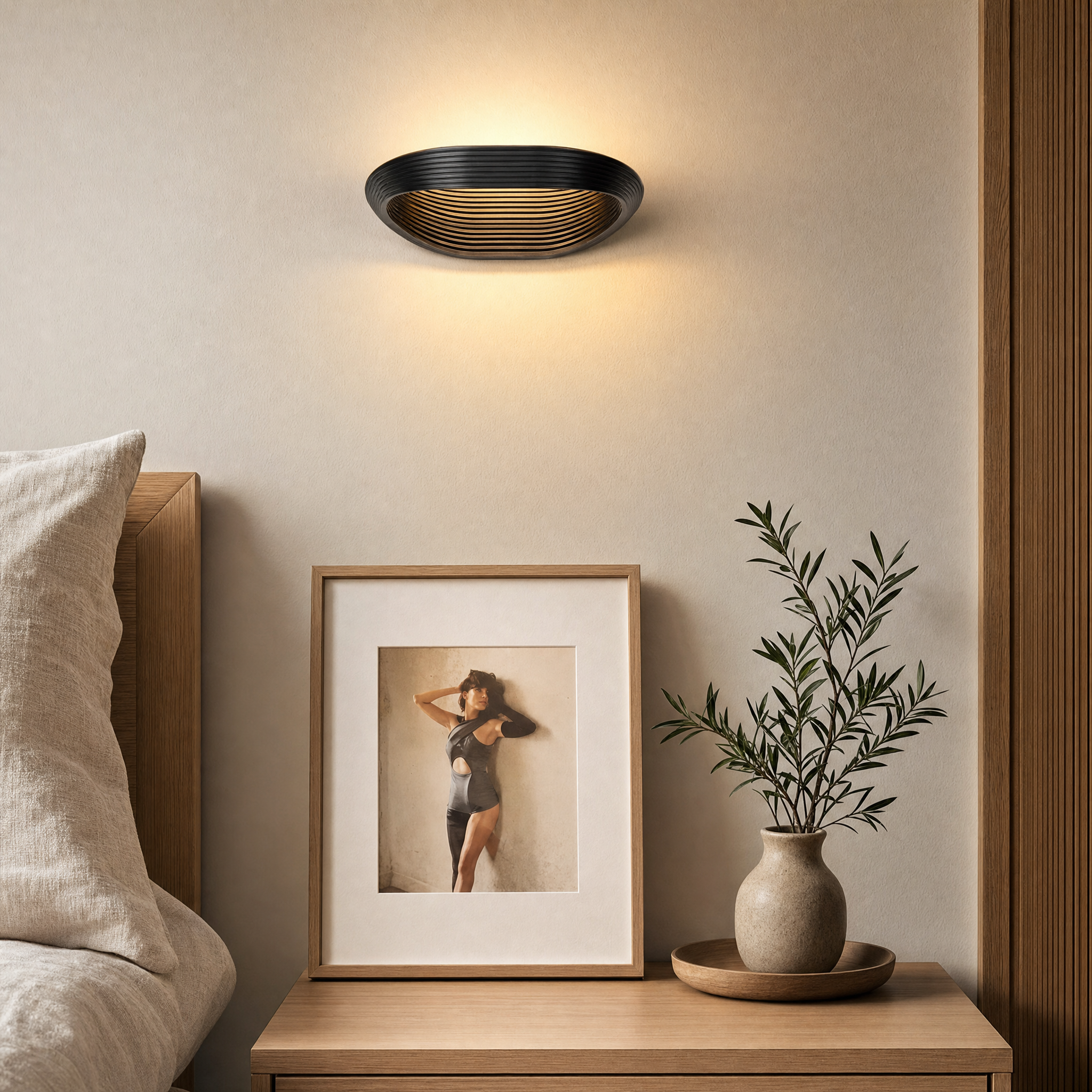 Black geometric wall sconce mounted in a hallway