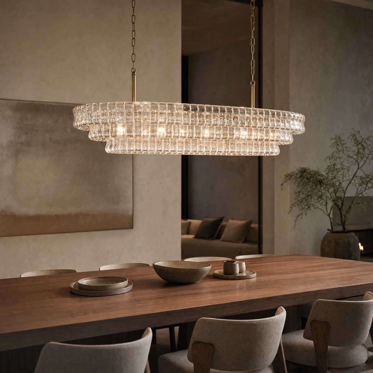 Ghiaccio oval chandelier hanging lengthwise above a long walnut dining table in a modern dining room