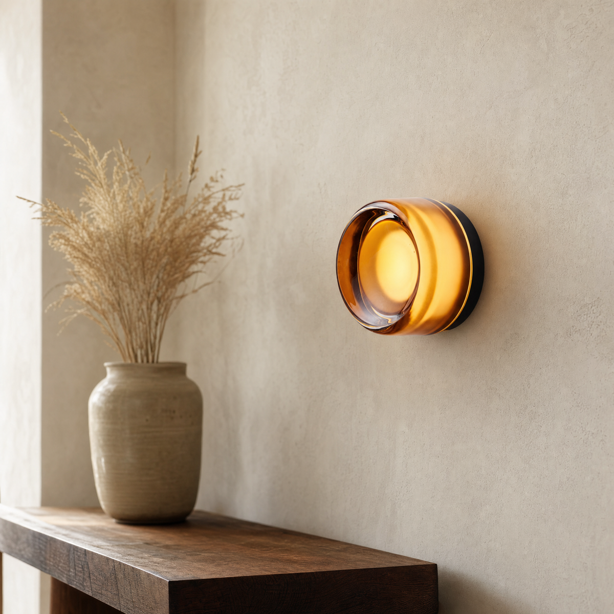 Vela modular wall sconce in Black Amber glowing on an ivory limewash wall above a dark oak console