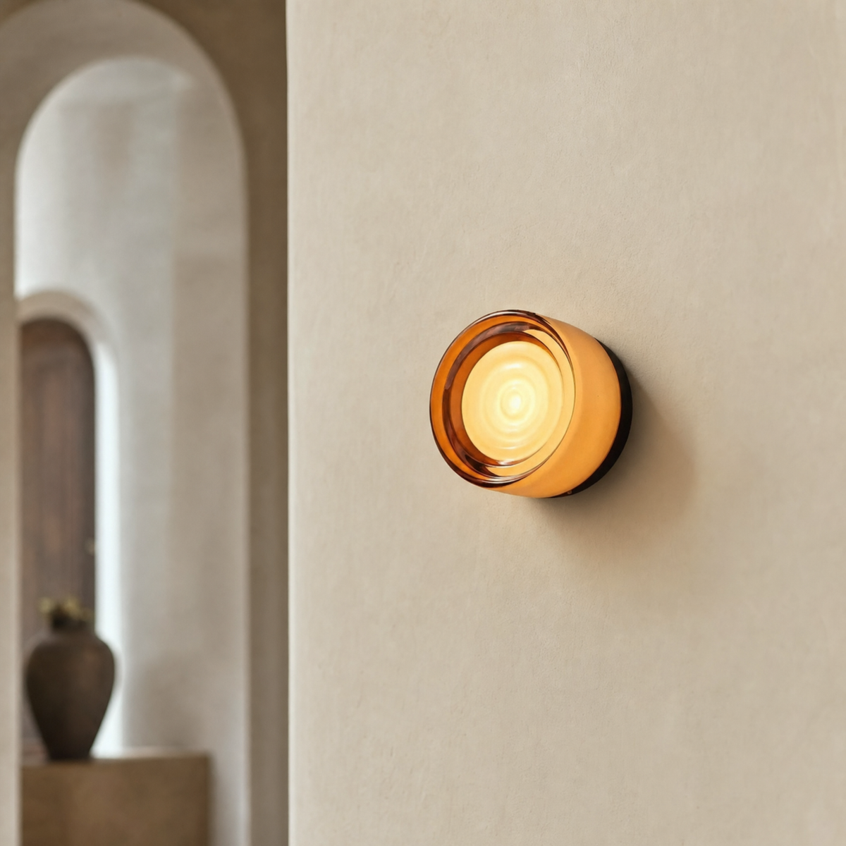 Vela modular wall sconce in Amber Wave on a cream limewash hallway wall with arched doorway