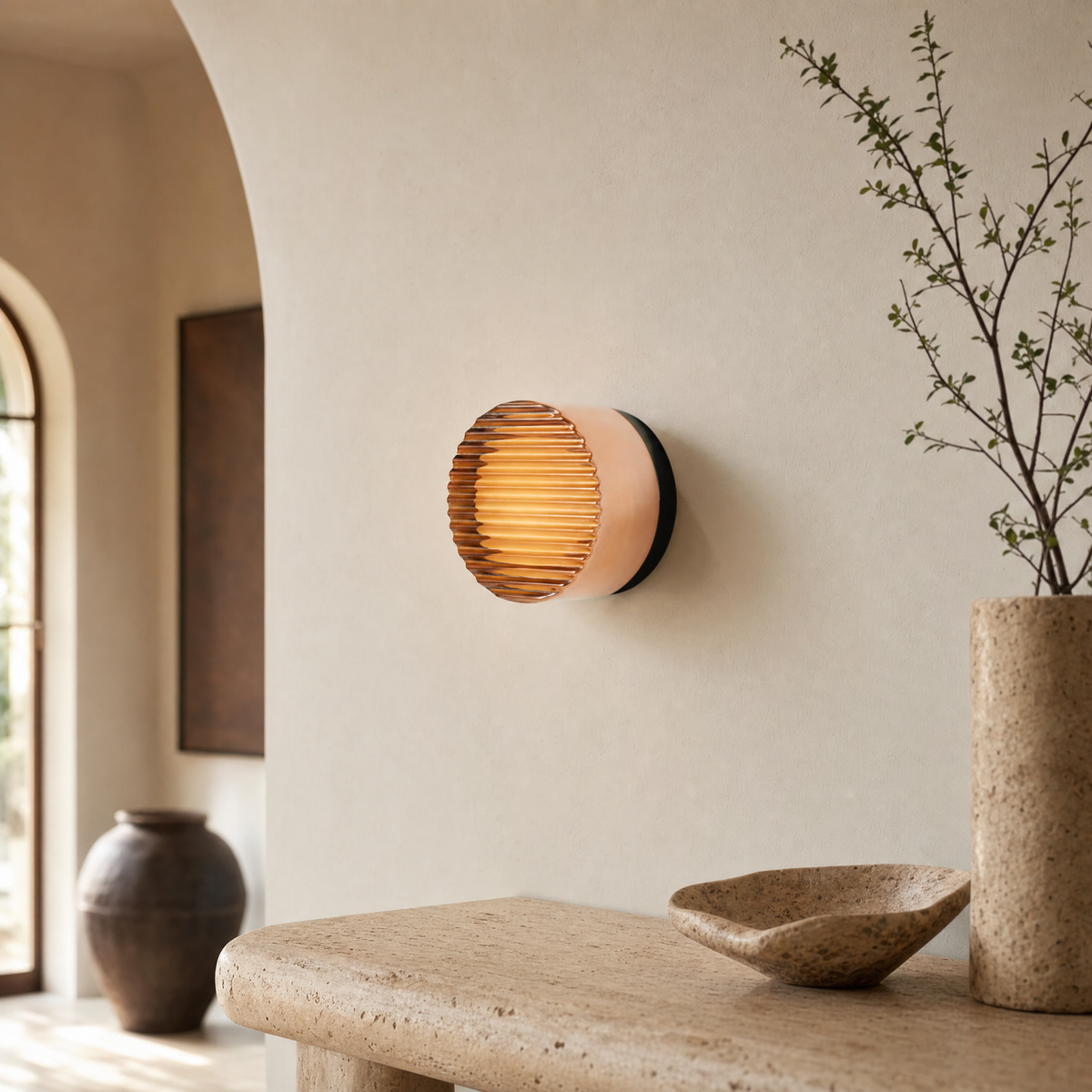 Vela modular wall sconce in Amber Ribbed above a travertine console in an upscale entryway